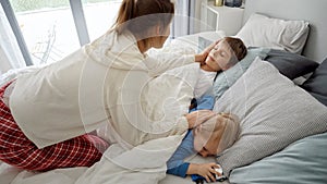 Young loving mother caressing her two sons sleeping in bed at morning. Concept of family happiness, relaxing at home, having fun