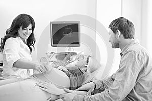 Young loving pregnant couple visiting doctor together monochrome