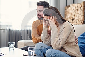 Young loving wife supporting her depressed husband during psychotherapy session with counselor, free space