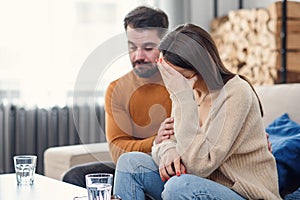 Young loving wife supporting her depressed husband during psychotherapy session with counselor, free space