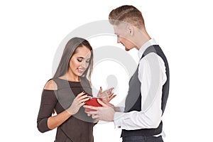 A loving man gives his girl a gift box with a ribbon, the girl is pleased and smiles. Valentine`s Day. Isolated.