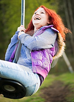 Young lucky girl is laughing while swinging