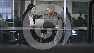 Young lustful man boss harassing his female colleague, caressing her knee under table at office, tracking shot