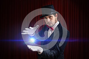Young magician man is showing bright ball that levitates