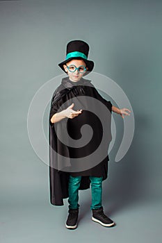 Young magician performing a trick. Little boy wearing top-hat and black magician cloak.