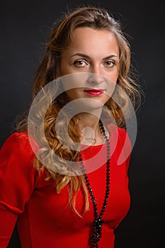 The young magnificent woman in an elegant dress of scarlet color with beautiful ringlets and a beads photo