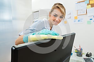 Young maid cleaning computer