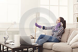 Young maid talking on phone during cleaning