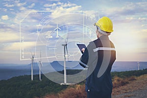 Young maintenance engineer team working in wind turbine farm at sunset on interface data