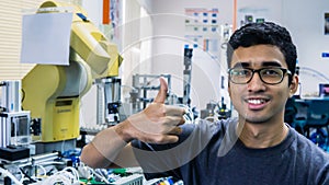 A young Malay engineering student with spectacles working in the lab and show a thumbs up sign