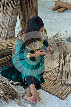 Young maldivian girl in national clothes playing with mobile phone