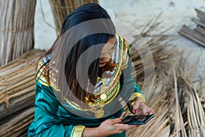 Young maldivian girl in national clothes using mobile phone