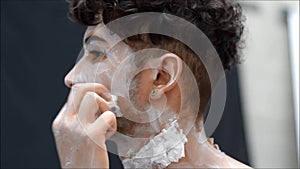 Young male actor or performer applying zombie make-up on his face