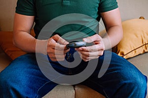 A young male adult is using a device to measure blood sugar while sitting on a couch