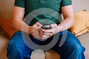 A young male adult is using a device to measure blood sugar while sitting on a couch