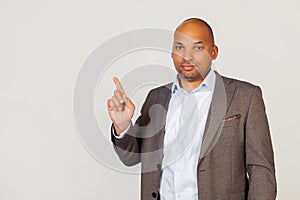 Young male African American businessman pointing his finger upwards with a smiling face. Pointing hand and finger to the