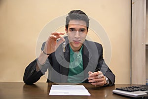 Young Male Agent Holding a Key at his Table