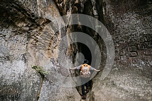 A young male amateur speleologist enters a mountain cave with a backpack