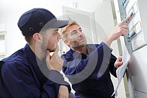 young male apprentice electrician listening to mentor