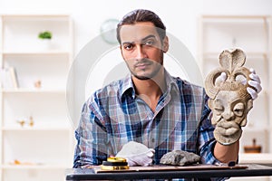 Young male archaeologist studying ancient african stonemask