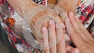 Young male arms comforting an elderly pair of old woman hands. Grandson and grandmother spending time together. Caring