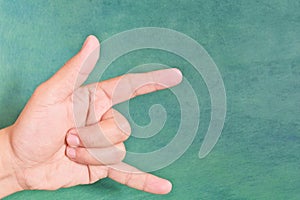 Young male Asian hand making i love you sign  on green background.