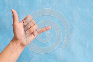 Young male Asian hand making shaka sign or call me sign  on blue background.