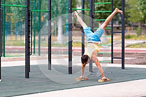 Young male athlete doing a handstand using handles