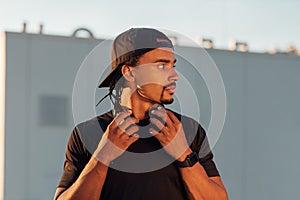 Young male athlete with dreadlock wearing a black hat