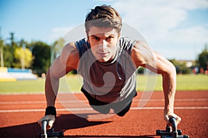 Young male athlete makes push ups on a racetrack