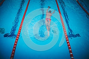 Young male athlete swimming freestyle in pool during competition
