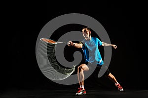 Young male badminton player over balck background