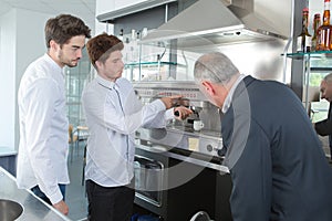 Young male baristas learning to use professional coffee machine