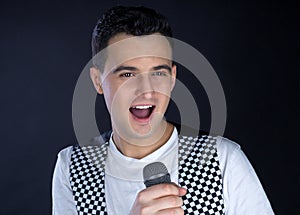 Young male black-haired pop singer sings to microphone