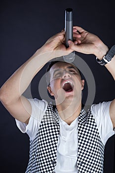 Young male black-haired pop vocalist performs singing to microphone