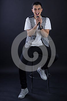 Young male black-haired singer posing singing to microphone