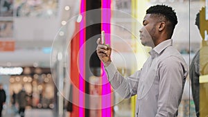 Young male blogger holding phone taking pictures using mobile application focused serious guy looks at smartphone screen