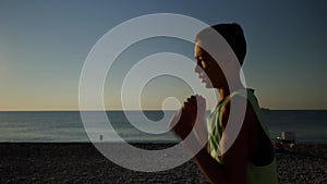 Young male boxer or karate fighter training on the beach during sunrise. Silhouette shot of boy doing shadow boxing in