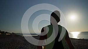 Young male boxer or karate fighter training on the beach during sunrise. Silhouette shot of boy doing shadow boxing in
