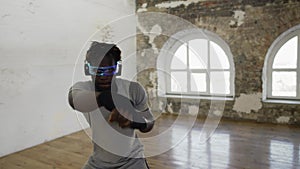 Young male boxer practicing shadow boxing in light sport studio