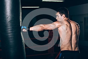 Young Male boxer using a punching bag in gym.