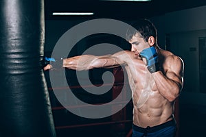 Young Male boxer using a punching bag in gym.