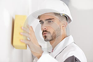 young male builder sponging wall surface