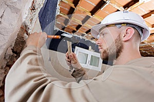 Young male builder using hammer chisel