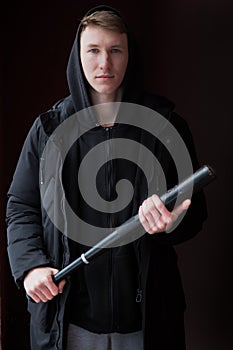 A young male bully with a baseball bat in his hands, looking at the camera.