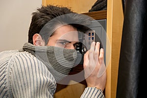 Young male burglar opening a small home vault or