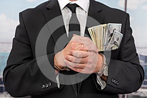 young male businessman in a classic suit and tie holds his hands in handcuffs.