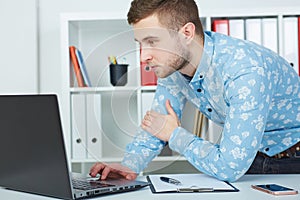 Young male businessman make notes looking at laptop sitting at office.