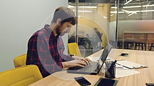 Young male businessman working on laptop in the office. Co-working  remote work  business  IT industry concept.