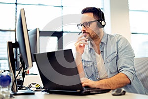 Young male call center operator working on his computer while hi